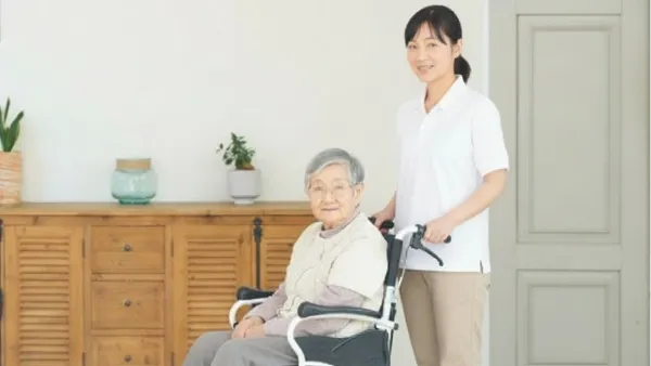 車いすに乗った老女を押す女性スタッフ